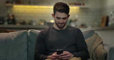 Cep telefonunu evde kanepede sörf gülen genç adam web.