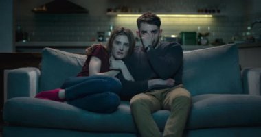 Korkmuş çift bir korkunç korku filmi izlerken gece geç bir kanepe üzerinde.