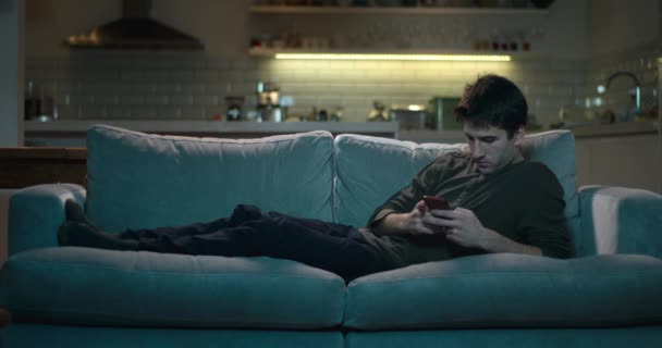 Mann Liegt Nachts Mit Handy Auf Sofa — Stockvideo