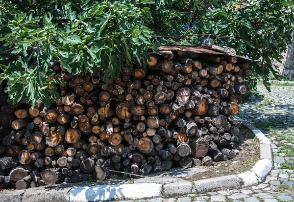 a bunch of firewood in the street under the tree