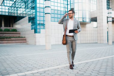 Gülümseyen ve dışında iş çizelgeleri tutan bir işletme Binası önünde duran genç başarılı iş adamı.