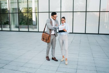 Genç iş adamları iş fikirleri ve dışında planları iş cam binası önünde tartışıyor.