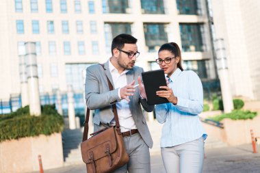 Söz, birlikte bir iş merkezi önünde ayakta dışında tablet ve iş planları kullanarak çalışan genç iş adamları.