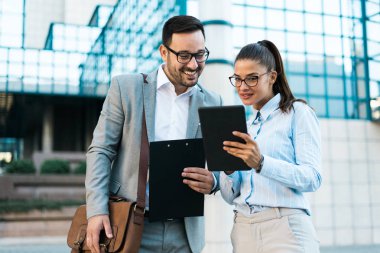 Söz, birlikte bir iş merkezi önünde ayakta dışında tablet ve iş planları kullanarak çalışan genç iş adamları.