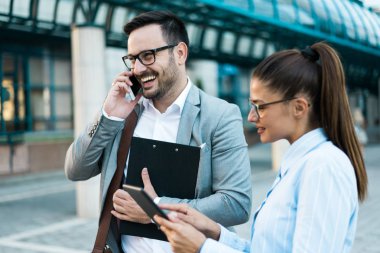 Birlikte, bir cam bina önünde tablet kullanan telefon ve iş kadın konuşurken işadamı çalışan genç başarılı iş adamları.