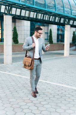 Seyir onun telefon ve gülümseyen genç başarılı iş adamı.