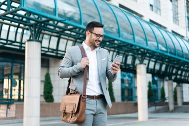 Seyir onun telefon ve gülümseyen genç başarılı iş adamı.