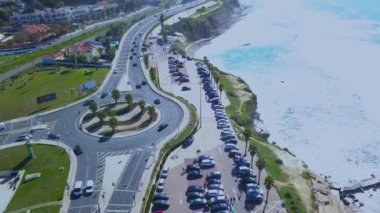 Havadan insansız hava aracı Atlantik sahilinin görüntüsü, izleme, kayalara çarpan dalgaların drone çekimi, Portekiz kıyılarında şehir manzarası ve arka planda plaj, güneşli bir günde, Cascais, Portekiz