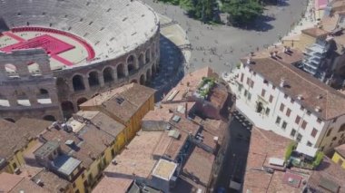 İtalya, Arena di Verona 'nın hava panoramik manzarası. İnsansız hava aracı fayanslı çatıları olan evlerin üzerinde uçuyor. Arena manzarası ve şehir açılıyor. 4k görüntüleme.
