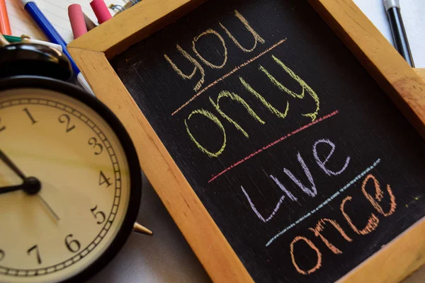 You only live once on phrase colorful handwritten on chalkboard, alarm clock with motivation and education concepts