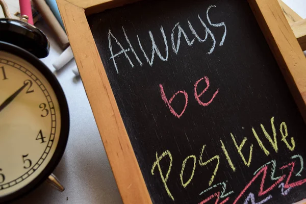 always be positive on phrase colorful handwritten on chalkboard, alarm clock with motivation and education concepts