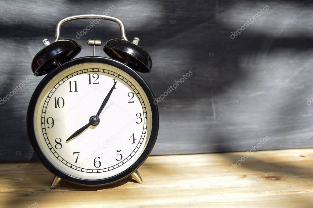 8 am/pm Back to school concept. Alarm clock on wooden with blackboard on background