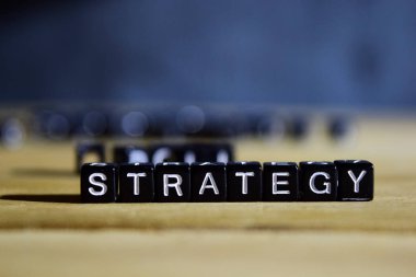 Strateji kavram tahta bloklar masanın üzerinde. Kişisel gelişim ve motivasyon kavramı ile bulanık veya siyah arka plan üzerinde