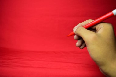 Kırmızı arka plan üzerine kırmızı kalem yazılı adam eli