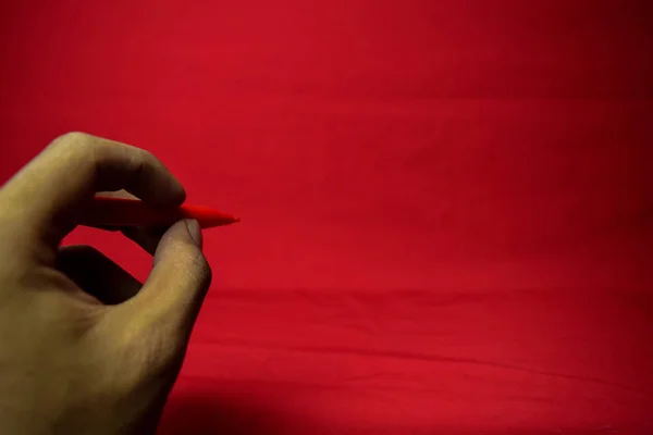 Man Hand Met Rode Pen Schrijven Rode Achtergrond — Stockfoto