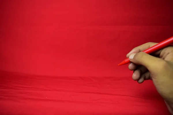 Man hand with red pen writing on red background