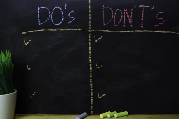 Do 's or Don' ts written with color chalk concept on the blackboard — стоковое фото
