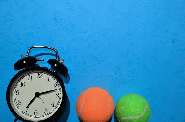 绿色和橙色网球 和闹钟指示蓝色背景的锻炼计划 顶部视图 具有任何设计的副本空间 健康健身理念 — 图库照片