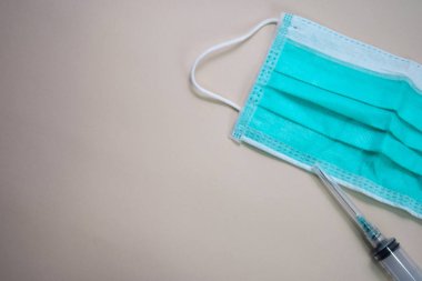 Kahverengi arka plan üzerinde izole koruyucu yüz yeşil maske ve şırınga kapatın