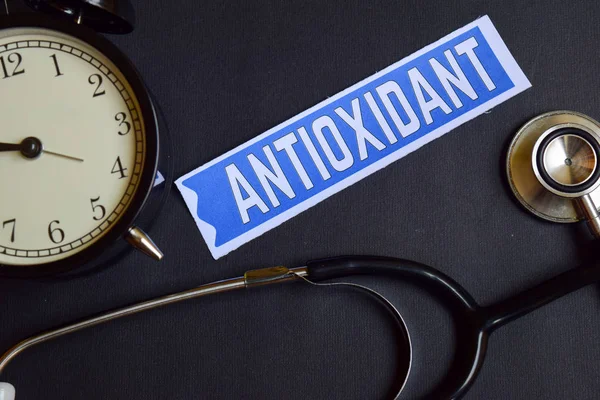 Antioxidante en el papel con Healthcare Concept Inspiration. reloj despertador, estetoscopio negro . — Foto de Stock