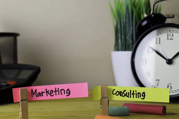Marketing and Consulting. Handwriting on sticky notes in clothes pegs on wooden office desk