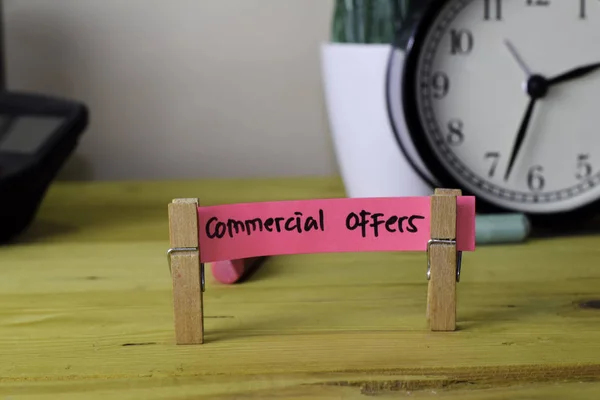 Commercial Offers. Handwriting on sticky notes in clothes pegs on wooden office desk