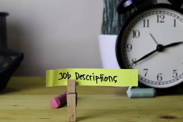 Job Descriptions. Handwriting on sticky notes in clothes pegs on wooden office desk