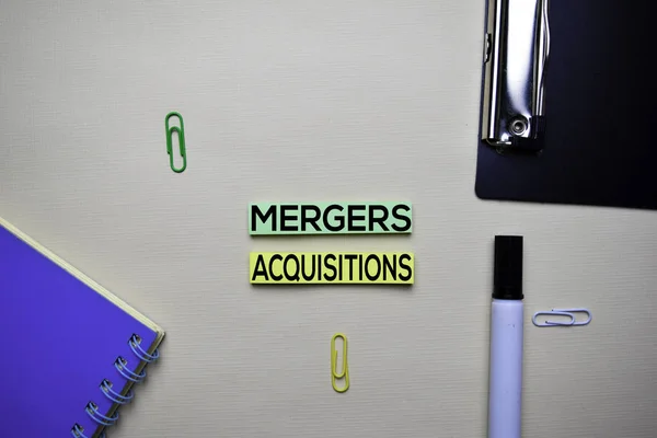 Mergers and Acquisitions text on sticky notes with office desk. Stock Market Exchange Concept