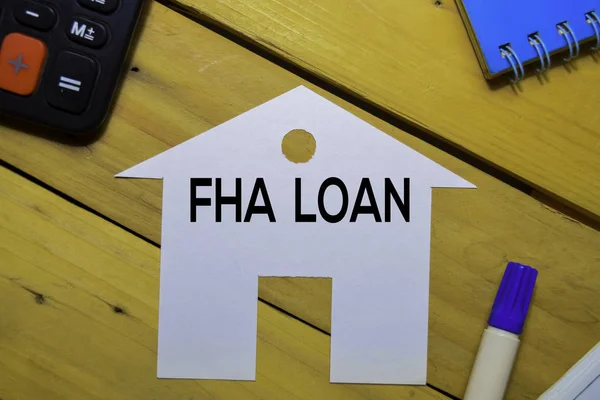 FHA Loan text on paper house isolated on office desk.