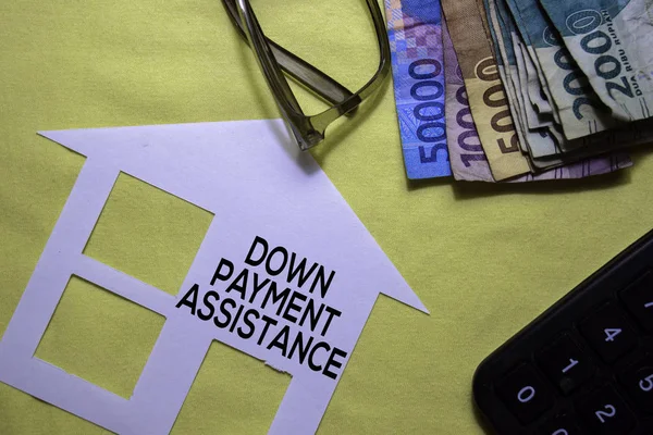 Down Payment Assistance text on paper house and Indonesian Rupiah isolated on office desk.