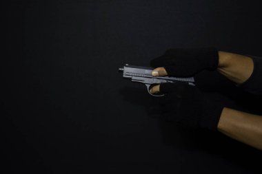 asyalı adam bir silah tutar. Siyah arka planda izole edilmiş hedefini vurarak öldürüldü.