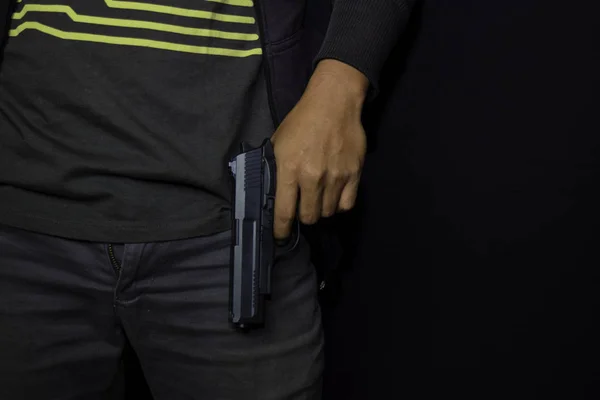 아시아 남자 는 총을 보유합니다. 검은 배경에 고립 된 그의 손에 총. — 스톡 사진