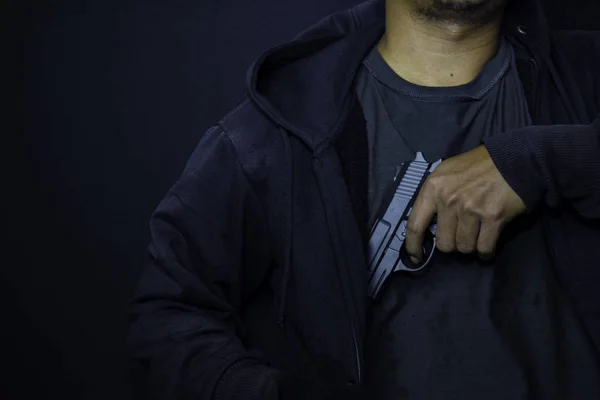 Asiático homem segurando uma arma. Pistola em sua mão fundo de uma jaqueta de couro — Fotografia de Stock