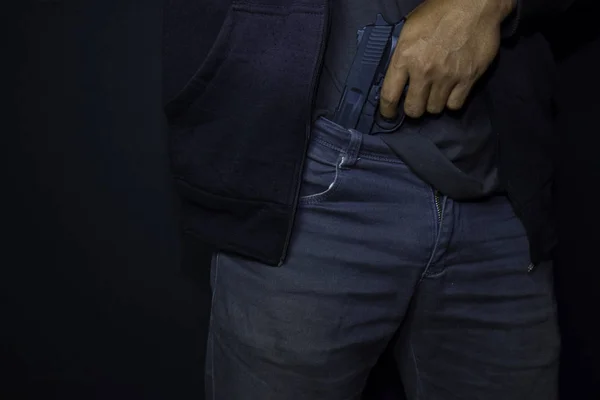 Asiático homem segura uma arma. arma em suas calças isolado no fundo preto . — Fotografia de Stock