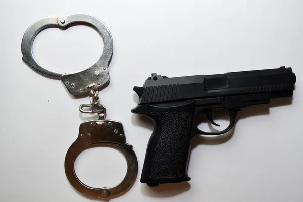 Schwarze Pistole und Handschellen isoliert auf weißem Hintergrund — Stockfoto
