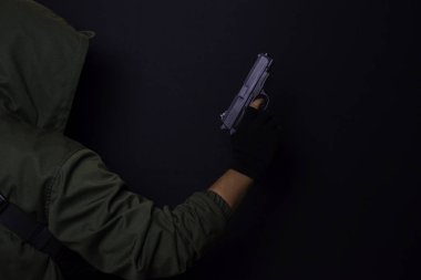 asyalı adam bir silah tutar. Elinde ki silah siyah arka plan üzerinde izole.