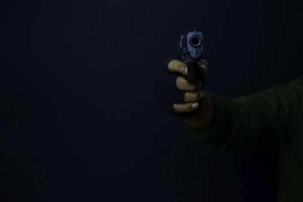 Азіатський чоловік тримає пістолет. Пістолет у руці. Вбитий стрілянина його мішень ізольовано на чорному тлі . — стокове фото