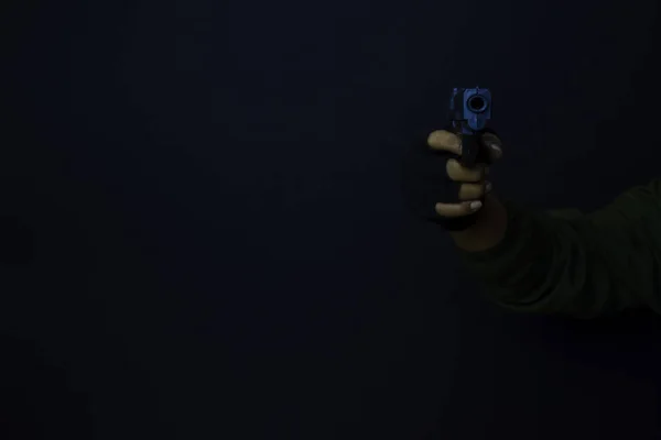 Азіатський чоловік тримає пістолет. Пістолет у руці. Вбитий стрілянина його мішень ізольовано на чорному тлі . — стокове фото
