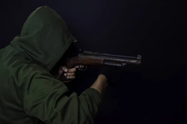 Азиат держит пистолет. Пистолет в руке. Убит стреляя по своей цели изолированы на черном фоне . — стоковое фото