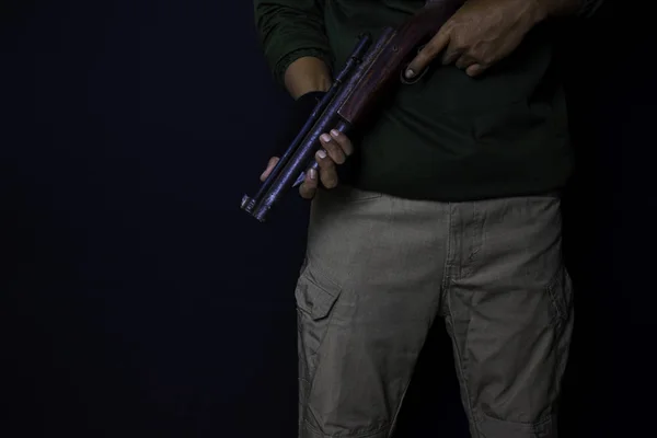 Asian man holds a gun. Gun in his hand isolated on black background. — Stock Photo, Image