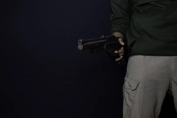 Asian man holds a gun. Gun in his hand. Killed shooting his target isolated on black background. — Stock Photo, Image