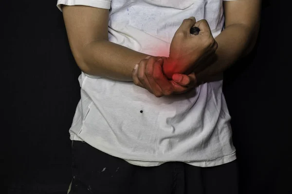 Homem asiático a segurar a mão. Ele sente dor no pulso com fundo preto. Conceito médico ou de saúde — Fotografia de Stock