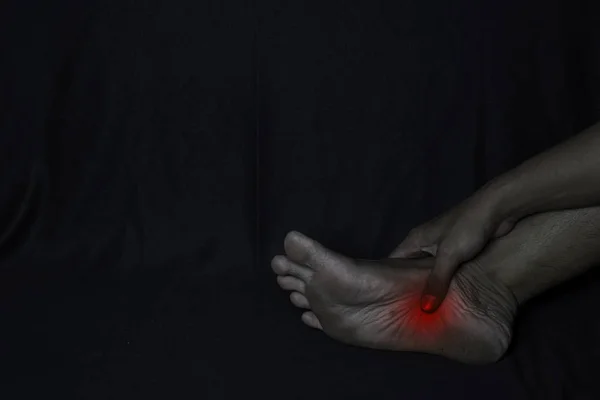 Hombre asiático sosteniendo su pie. Siente dolor en el talón del pie con fondo negro. Fascilitis plantar. Concepto médico o sanitario —  Fotos de Stock