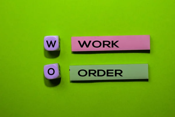 WO - Trabajo Orden acrónimo escribir en notas adhesivas aisladas sobre fondo verde . — Foto de Stock