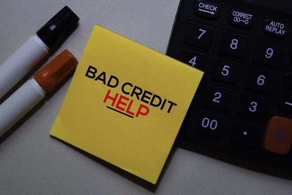 Bad Credit Help text on sticky notes with calculator on office desk.