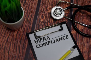 HIPAA Compliance write on paperwork isolated on wooden table.