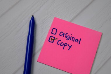 Copy and Original write on a sticky note. Supported by an additional services isolated wooden table. clipart