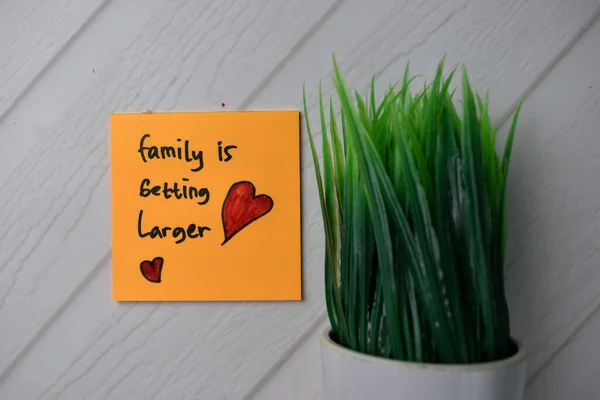 Family Is Getting Larger text on sticky notes with office desk.