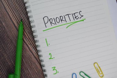 Öncelikler yapışkan bir nota yazılır. Ek hizmetler tarafından desteklenen izole ahşap masa.