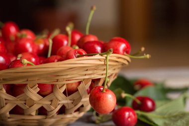 Tahta arka planda yaprakları olan bir sepet tatlı ve olgun kiraz.